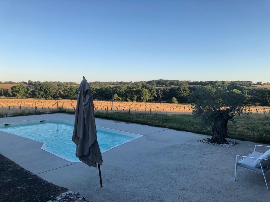 Une piscine privée à l'eau turquoise ouvrete sur un champ. Parasol replié et transat au premier plan. Font Valley, gîtes à la ferme.